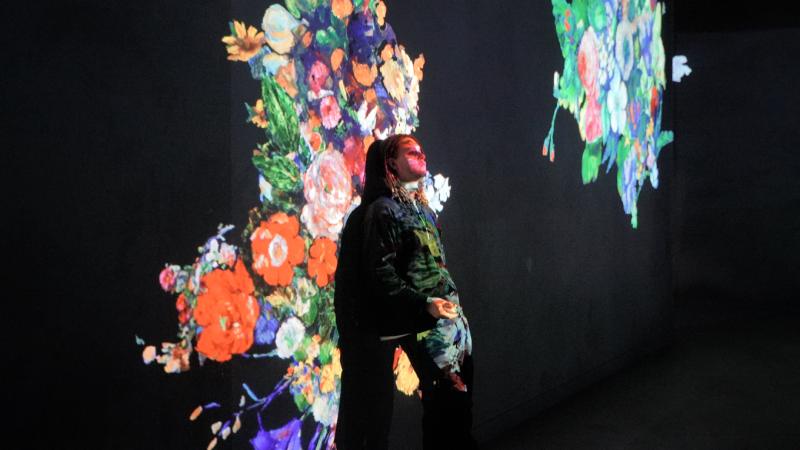 Etudiante devant des animations florales à l'atelier des lumières